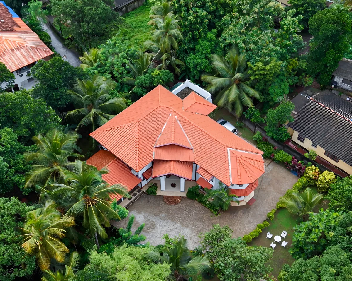 Aerial view of the red-roofed home surrounded by trees and garden