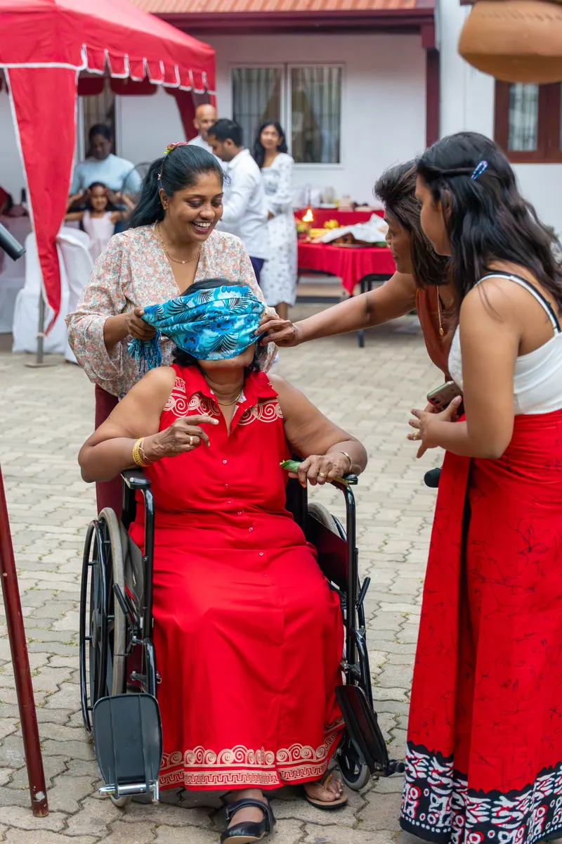 A blindfolded resident in a wheelchair laughs as caregivers guide the pot-breaking game