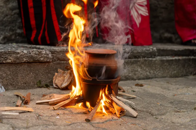 A clay pot of milk rice boiling over a wood fire