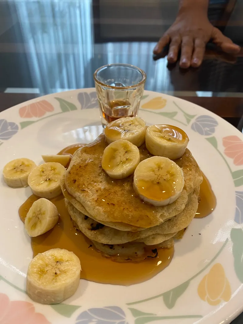 A plate of banana pancakes with treacle and fresh banana slices