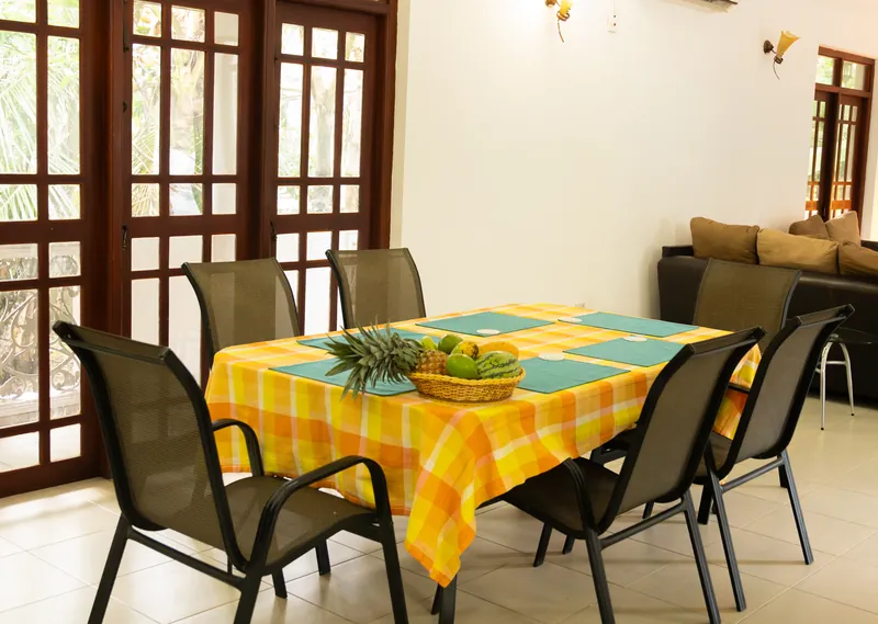 A dining table with fresh fruit and teal placemats near open garden doors