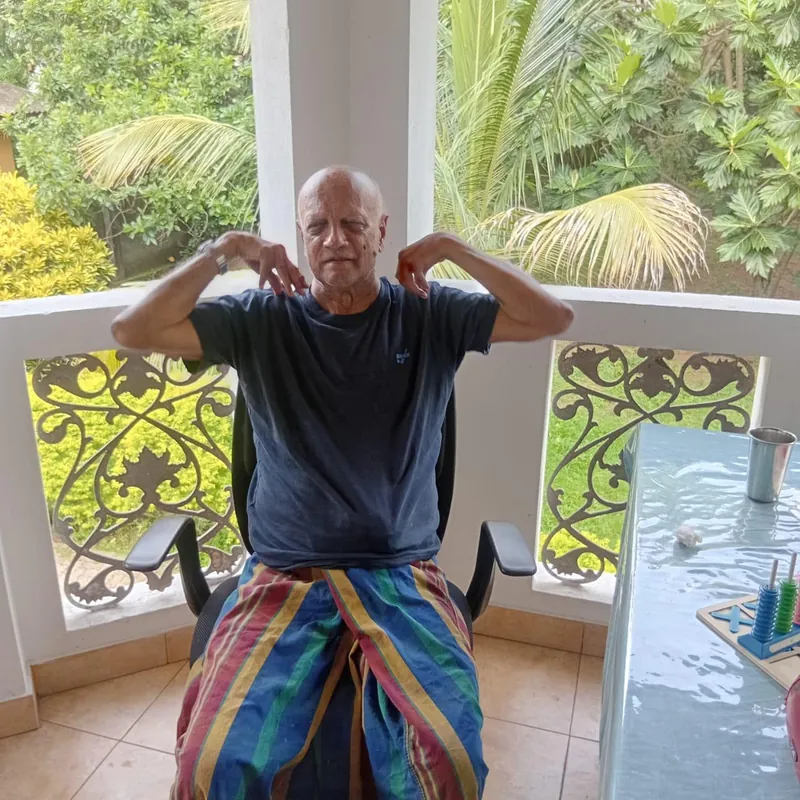 A resident doing seated arm exercises on a balcony