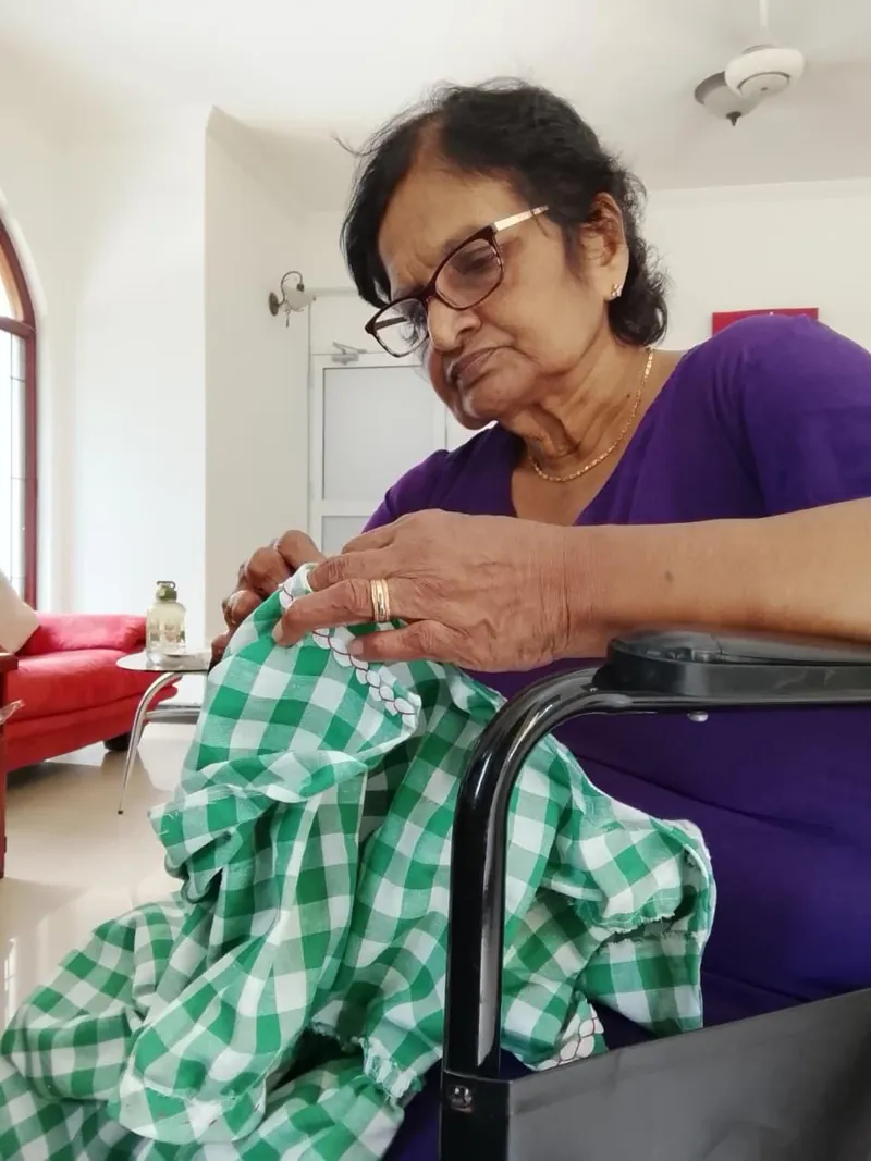 A resident in a wheelchair doing needlework on gingham fabric