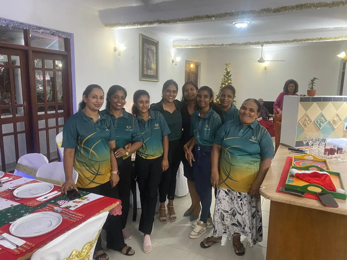 Caregivers in Golden Hands shirts smiling together at the Christmas celebration