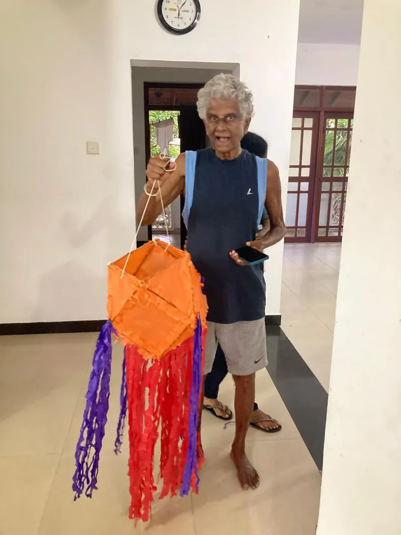 A resident proudly holds up his finished orange Vesak lantern