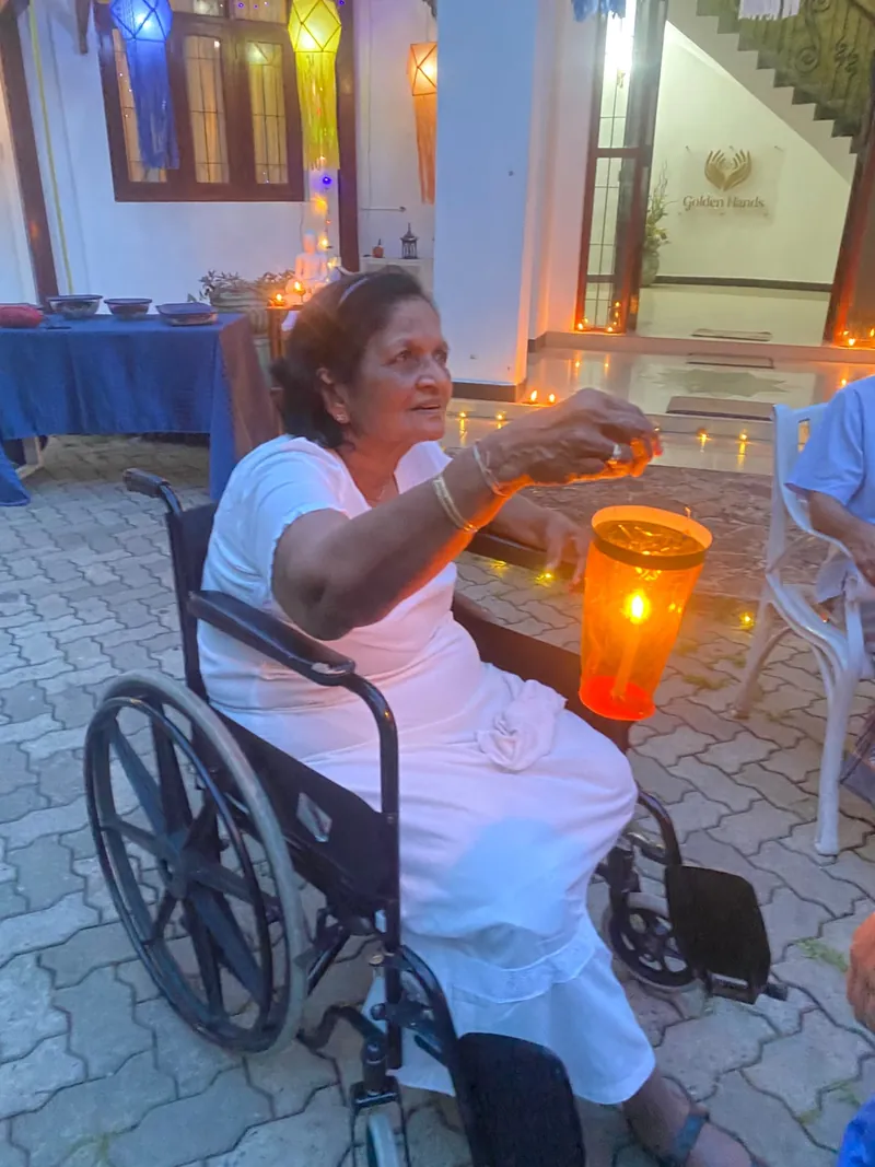 A resident in white holds a glowing orange lantern from her wheelchair